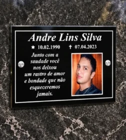 Placa de túmulo retangular preta com foto, nome, datas e mensagem, fixada em granito
